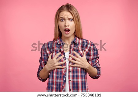 Studio shot of discontent female keeps hands on breast, displeased to hear bad comments from men, talking about her bosom size. Unhappy beautiful woman with shocked expression, isolated on pink Royalty-Free Stock Photo #753348181