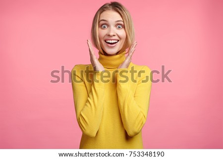 Excited blonde female smiles happily, gestures actively, rejoices her victory on competition, expresses positiveness. Joyful young woman glad to hear pleasant news about her promotion in work