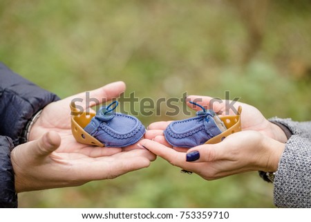 Conceptual photo of a couples hands holding baby shoes in anticipation of the child