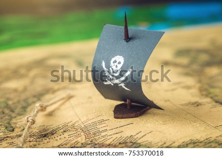 Toy boat pirate flag skull and bones on the world map of the playing field handmade Board games. The concept of piracy
