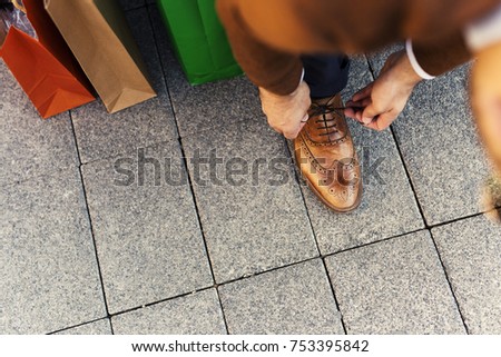 Man at the shopping having pause and tying shoes