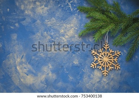 Christmas background: wooden decorative snowflake and spruce branch  on a blue and golden background