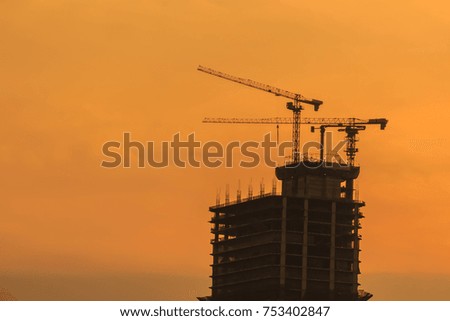 High-rise condominium building under construction in blue and yellow sky background. Silhouette riverfront view of real estate development.