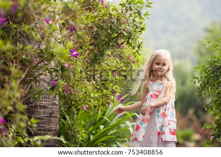 Adorable toddler girl walking in flowers. Natural light. Flowing hair.