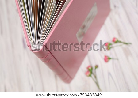 photo?book with a hard cover on a wooden surface
pink photo album with leatherette with a shield
Expanded photo book pages
open photo album
leather photo book in the box