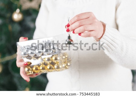 Close up of woman hands holding christmas goold ball. Decoration, holidays and people concept.