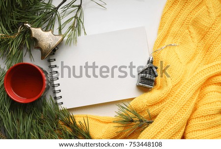 Christmas background with a Cup  of coffee, a notebook, Christmas toys, branches of pine with large needles and a yellow sweater. Top view, close-up 