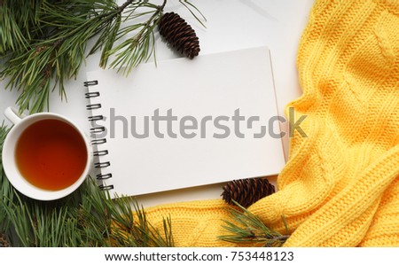 Christmas background with a Cup of tea, a notebook, fir cones, branches of pine with large needles and a yellow sweater. Top view, close-up 