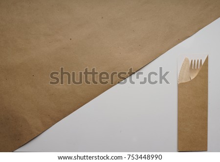 Composition of Kraft brown wrapping paper on white and wooden fork and spoon in paper packaging. Geometric background. Bright typographic design layout, covers, brochures, banners. Top view, close-up 
