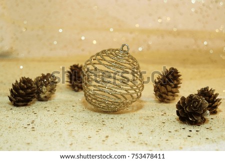 Gold shiny decorated bauble with cone pines and sparkling golden glitter blur background for the Christmas festive