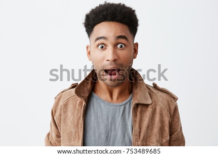 What. Close up of young shocked black-skinned man with afro hairstyle in casual stylish outfit looking in camera with opened mouth and raised eyebrows, being surprised win lottery