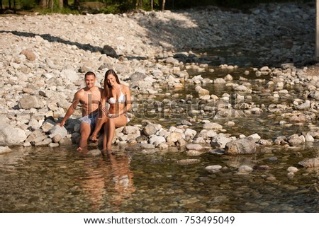 Active couple rests on river bank on a hot summer day