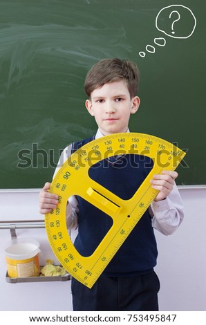 A puzzled boy with angle protractor at classroom board