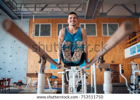 sportsman has workout with gymnastics bar; young handsome guy exercising in oldschool gym;