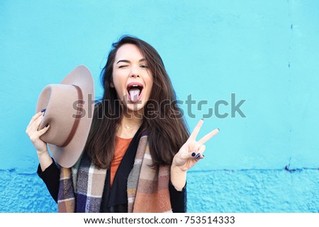 Fashion autumn portrait woman in trendy hat on a blue background