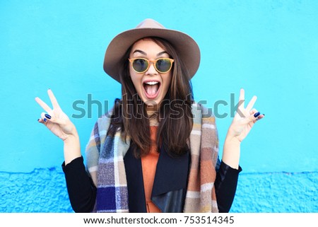 Fashion autumn portrait woman in trendy hat on a blue background