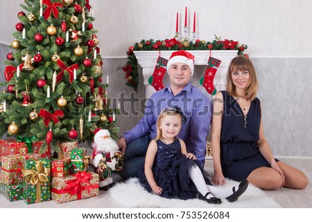 Christmas or New year celebration. Happy young family at the Christmas tree with a fireplace