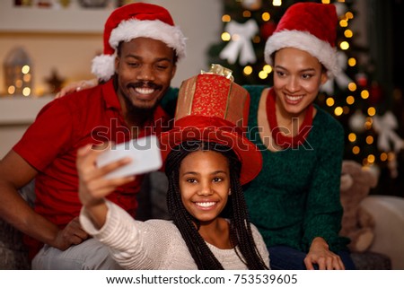 Cute little girl with her parent taking selfie on Christmas
