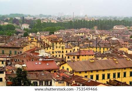 From the guinigi's tower a landscape aerial view of the roofs of the medieval town of Lucca in Tuscany, Italy . The urban sign of the old amphitheater now become a square, is visible