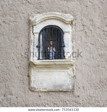 small mary or madonna sculpture with child in a latticed niche in a rustic plastered wall, Christian Catholic religion symbol, typical of southern Europe in the countryside, copy space