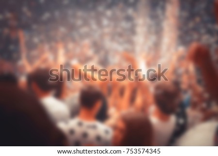 Blurred for background. night party festival crowd of people silhouettes hands up with confetti. Nightclub party. Colorful lights during dj party at concert in night club.