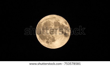 Bright Full-Moon phase with many craters and a small cloud in a dark sky.
