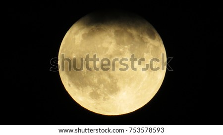 Bright Full-Moon phase with many craters and a dense cloud in a dark sky.
