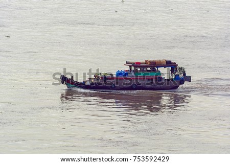 Old style wooden river boat of floating vendor selling various fruits and snacks to cargo ship's crew.