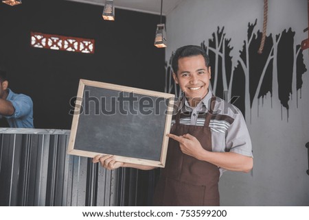coffee shop waiter holding blackboard sign in front of his cafe