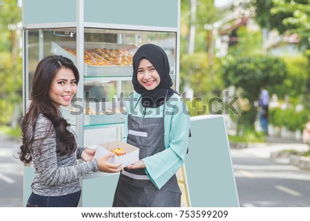woman buying fresh cake at halal food stall. street food concept Royalty-Free Stock Photo #753599209