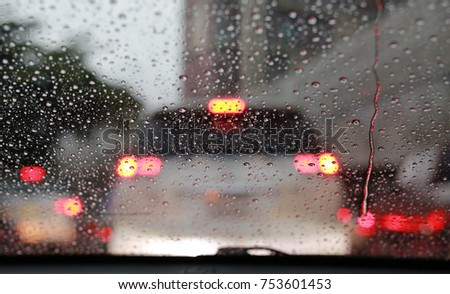 Abstract rain drop on glass with blurred traffic in raining day on the road view through car