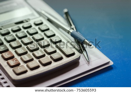 Close up calculator and pen business Accounting, on a blue background.