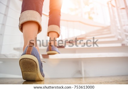 Young adult woman walking up the stairs with sun sport background. Royalty-Free Stock Photo #753613000