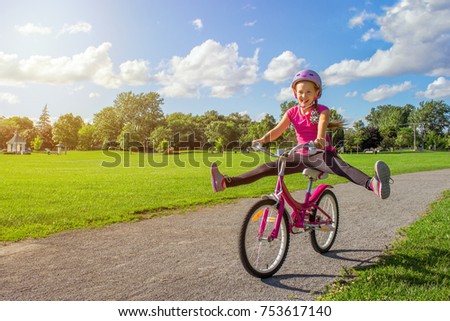 Girl in a helmet riding a bicycle. Cyclist in summer park.