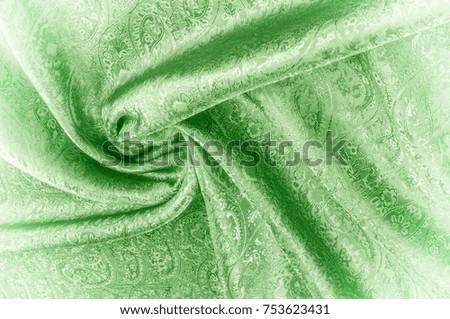 Background texture, pattern. Paisley Silk green Jacquard is a complex woven glossy fabric with a woven design. Weaving creates the effect of a "shadow" pattern or print.