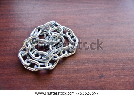 Close-Up View of Pile of Metal Chain Isolated on Wooden Table