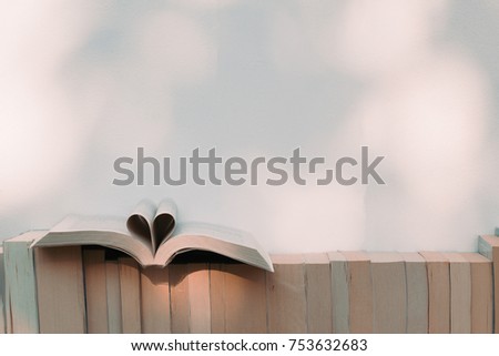 Open book in heart shape and books on the shelf in the library
