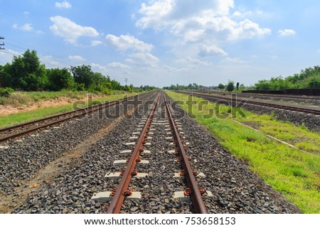 green landscape with railroad to horizon and blue sky with clouds over it