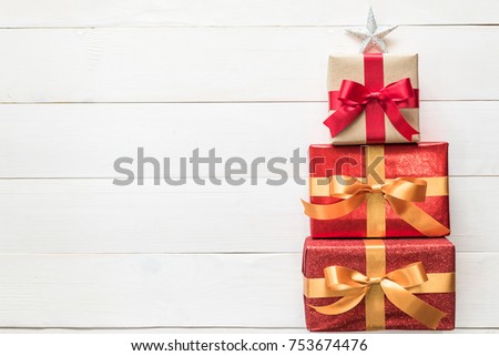 Gift box present stack in Christmas tree shape with red-gold luxury ribbon, star top on white pine wood backdrop for Xmas boxing day and winter holiday seasonal celebration background Royalty-Free Stock Photo #753674476