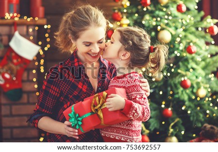 happy family mother and daughter giving christmas gift and embracing