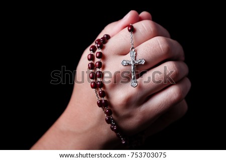 Female hands praying holding a rosary with Jesus Christ in the cross or Crucifix on black background. Woman with Christian Catholic religious faith Royalty-Free Stock Photo #753703075