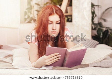 Beautiful woman in bed, bedroom lying with book, textbook and reading. A disheveled, shaggy look. Girl with red hair and Irish Scottish roots. Good morning.