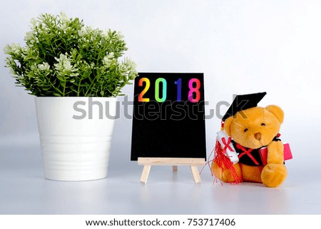 Number year 2018 on mini black board with convocation teddy bear decorated on white background.