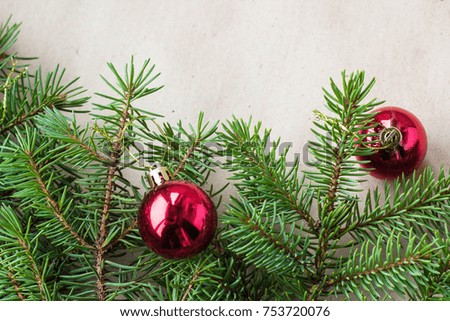 Fir tree branches decorated with red christmas balls as border on a rustic holiday background frame with copy space.
