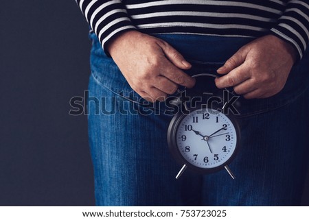 Time is passing or biological clock, female hand holding stylish black vintage alarm clock, selective focus. Concept of reproductive health control for women.