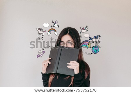 An Asian Student Woman wearing glasses reading a book and glancing at unicorns and rainbows illustration doodles- imagination concept  