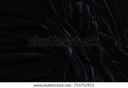 Dark black velvet fabric, wave, draperies. Beautiful textile backdrop to create creative layouts for black Friday. Close-up. Top view