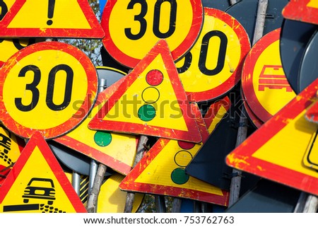 Many road signs stacked together waiting to be used again