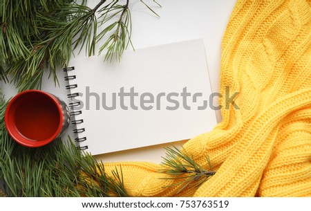 Christmas background with a Cup  of tea, a notebook, branches of pine with large needles and a yellow sweater. Top view, close-up 