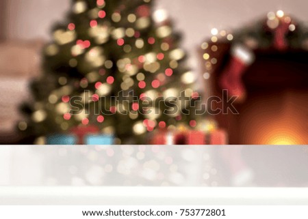 A table with space for your advertisement. Christmas tree with lights. House Interior.